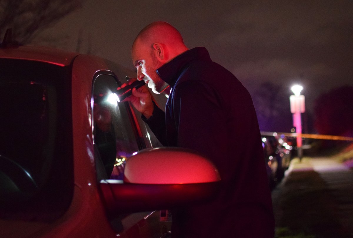 Homicide detective Sgt. Matthew Tobjy peers inside of a vehicle that investigators connected to a deadly shooting in Baltimore's Belair-Edison neighborhood. Police said a man was shot in the 4300 block of Shamrock Avenue