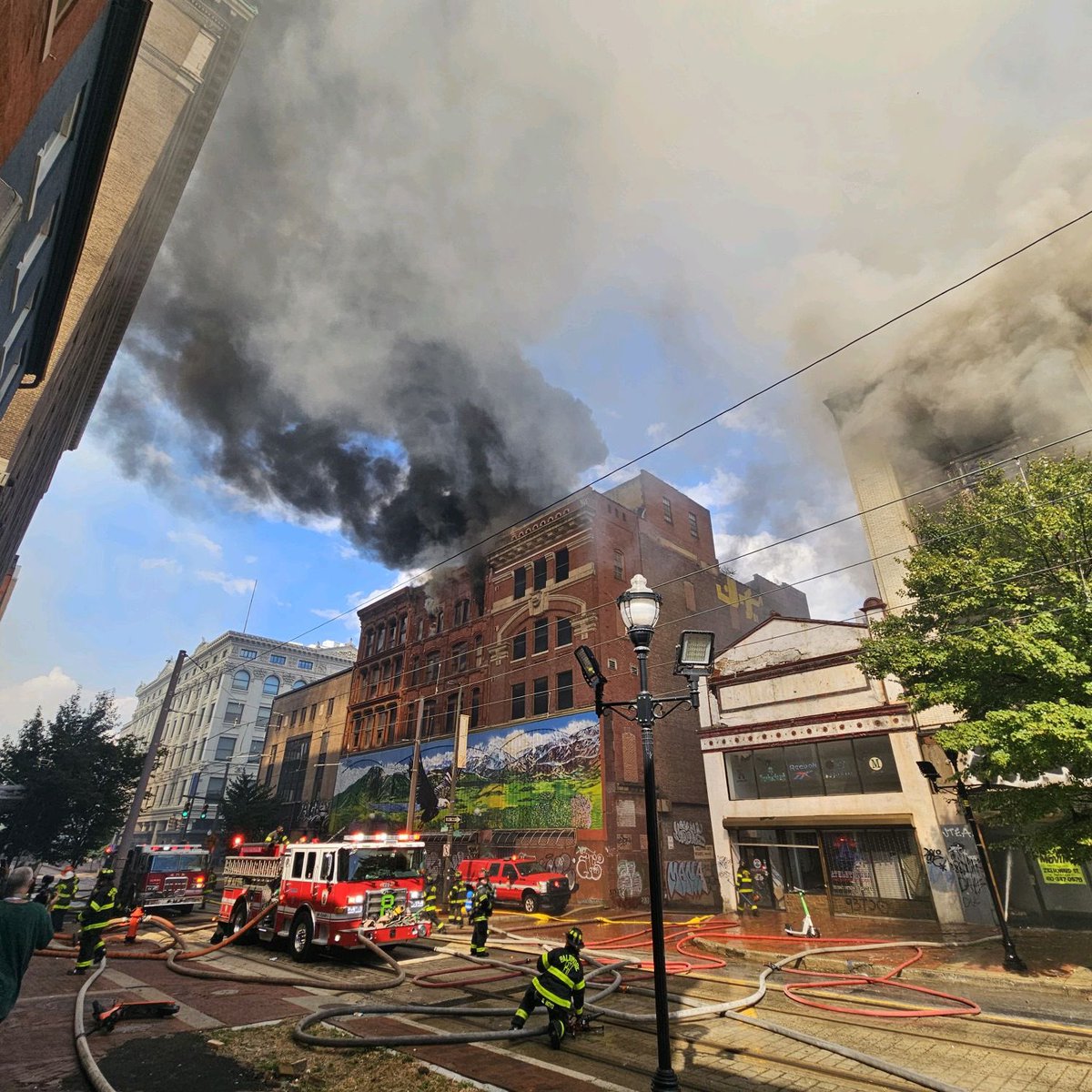 The fire has escalated to a 4th alarm and now involves another block of buildings. @mtamaryland Light Rail has been shut down. 
