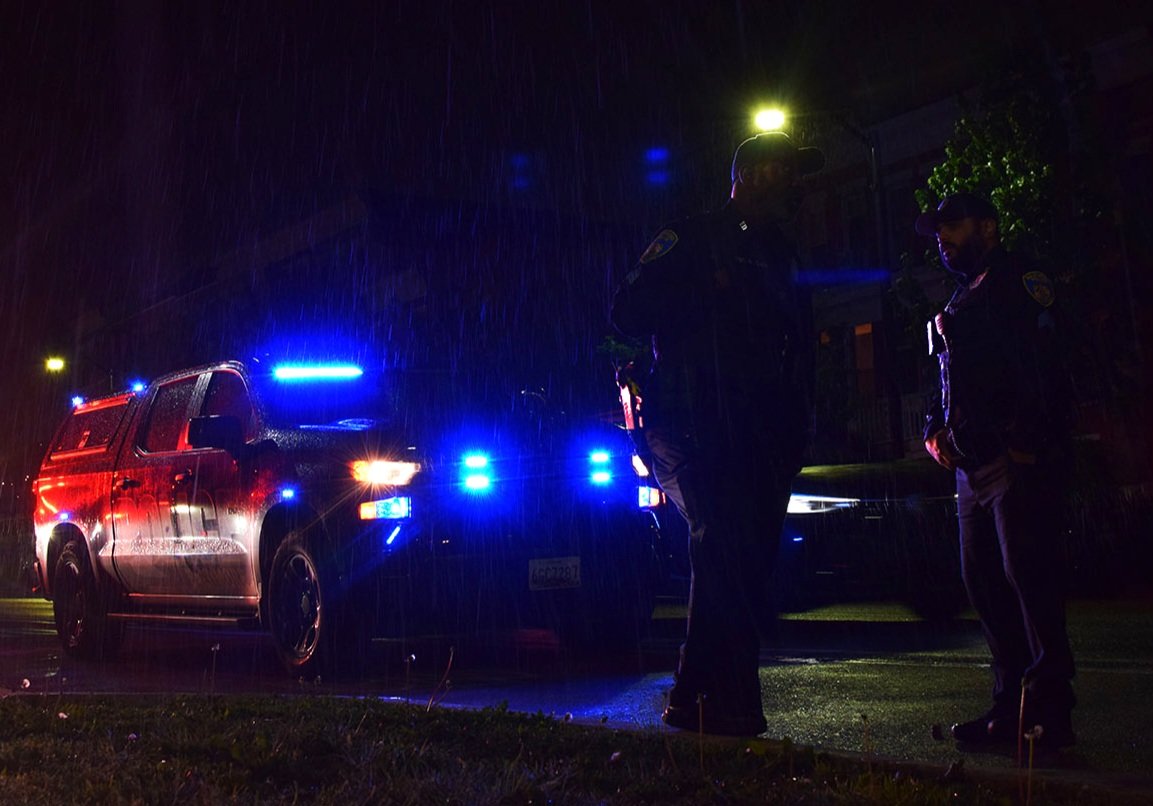 Officers stand in the rain next to the 1800 block of North Durham Street after a man was fatally shot The man was one of three people injured by gunfire in four hours.